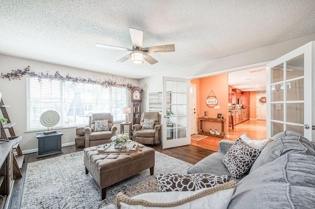 living area featuring ceiling fan, a textured ceiling, wood finished floors, baseboards, and french doors