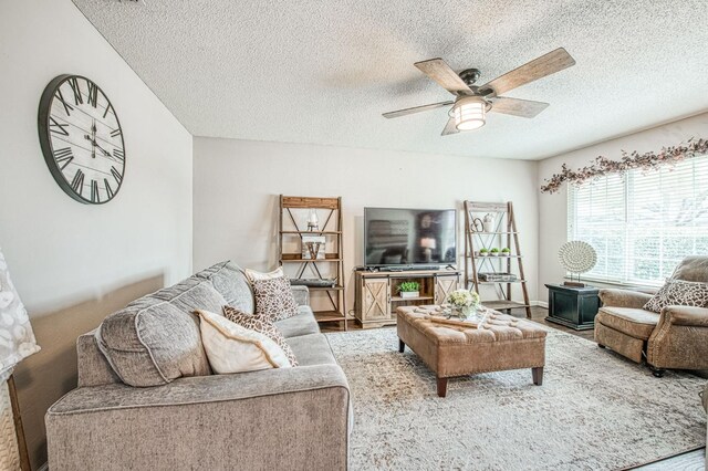 living room with a textured ceiling, a ceiling fan, and wood finished floors