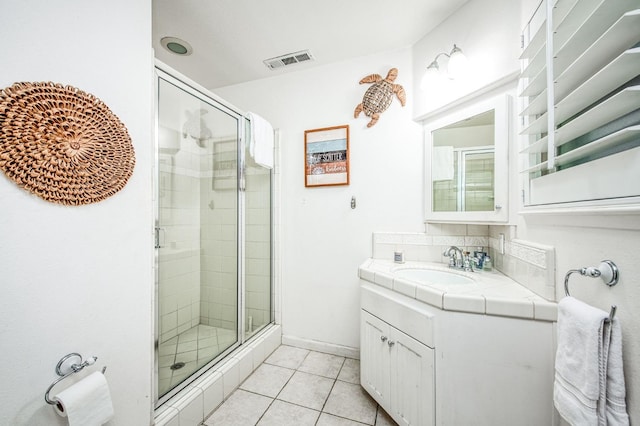 bathroom featuring visible vents, a stall shower, vanity, baseboards, and tile patterned floors