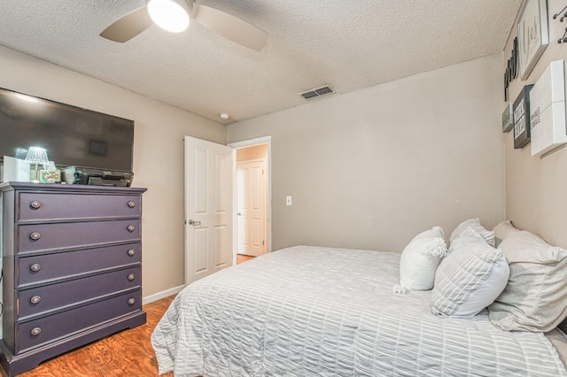 bedroom with visible vents, baseboards, a ceiling fan, a textured ceiling, and light wood-style floors