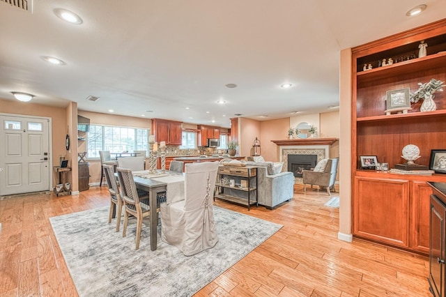 dining room with light wood finished floors, recessed lighting, and a tile fireplace