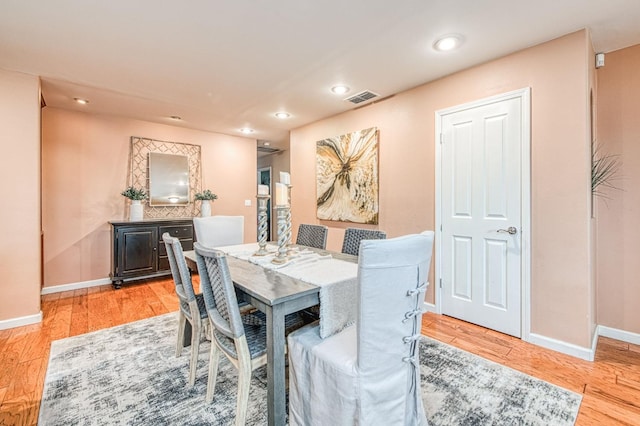 dining room featuring light wood-type flooring, visible vents, and baseboards