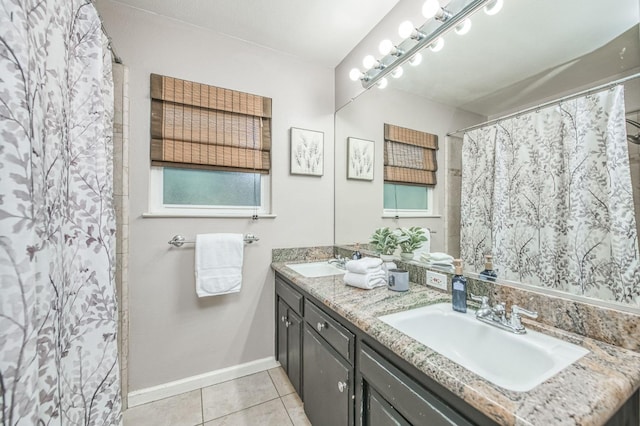 bathroom with baseboards, double vanity, a sink, and tile patterned floors