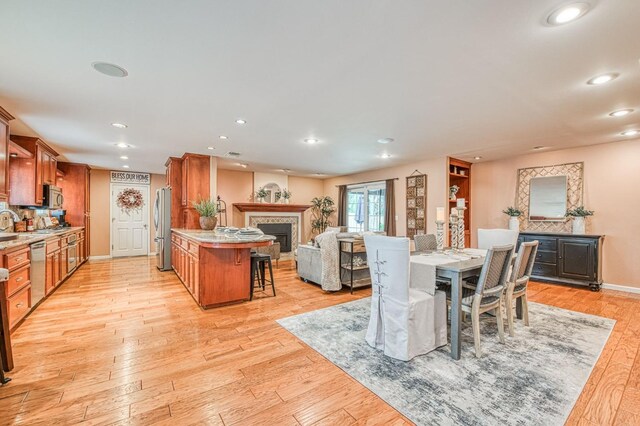 dining area with light wood-type flooring, a fireplace, and recessed lighting