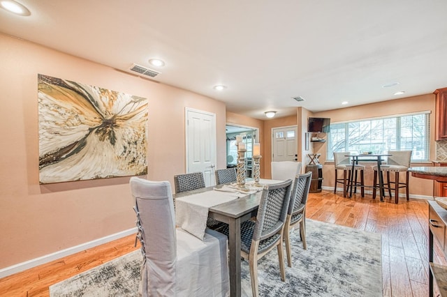 dining space featuring light wood-style floors, baseboards, and visible vents