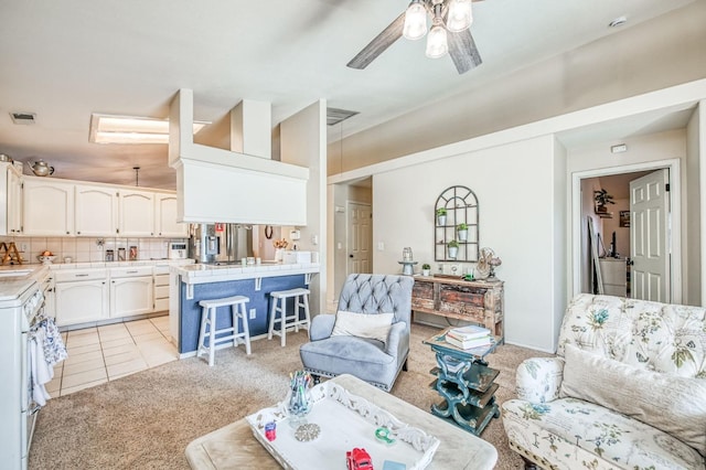 living area featuring light tile patterned floors, visible vents, a ceiling fan, and light colored carpet