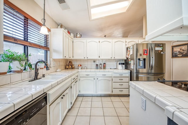 kitchen featuring tile countertops, appliances with stainless steel finishes, and white cabinets