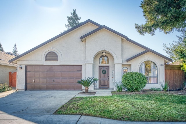 view of front of property featuring driveway, a front yard, an attached garage, and stucco siding