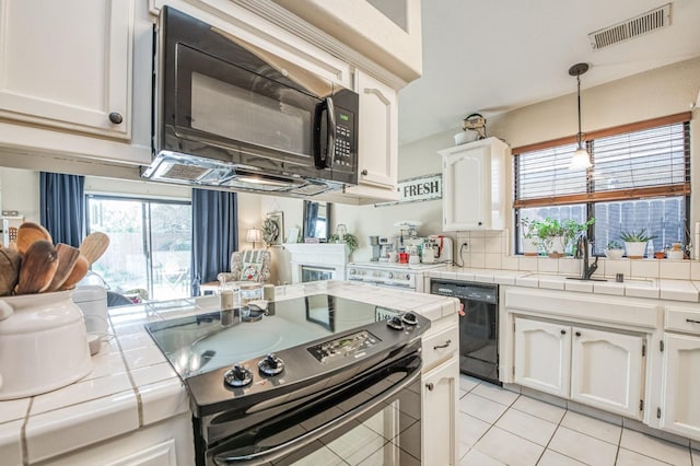 kitchen featuring tile countertops, black appliances, visible vents, and a healthy amount of sunlight