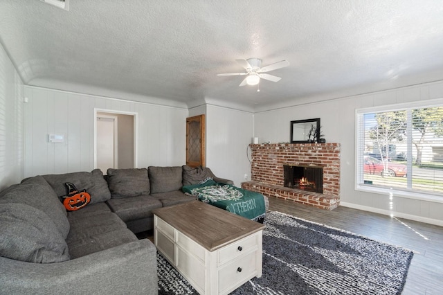 living room featuring ceiling fan, a fireplace, dark hardwood / wood-style flooring, and a textured ceiling