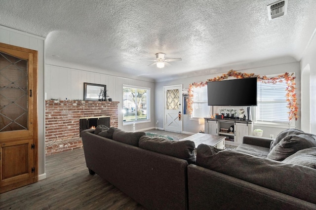 living room with ceiling fan, dark wood-type flooring, a fireplace, and a textured ceiling