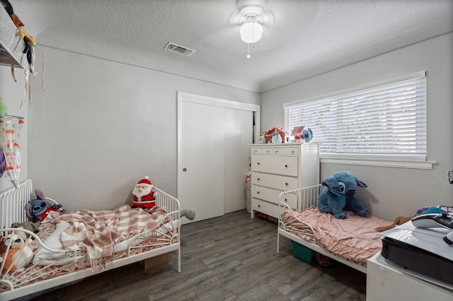 bedroom with a textured ceiling, dark wood-type flooring, and ceiling fan