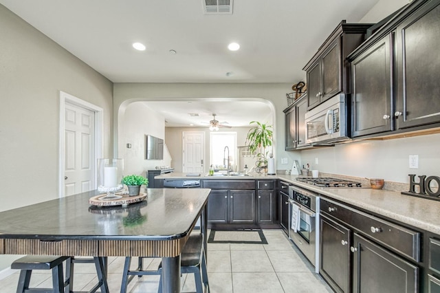 kitchen with light tile patterned flooring, dark brown cabinetry, sink, appliances with stainless steel finishes, and ceiling fan