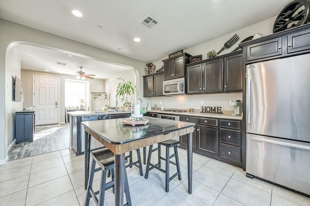 kitchen with ceiling fan, appliances with stainless steel finishes, dark brown cabinets, and light tile patterned floors