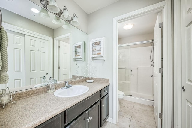 bathroom featuring vanity, toilet, a shower with shower door, and tile patterned flooring