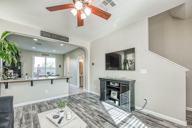 living room with ceiling fan, sink, and hardwood / wood-style floors