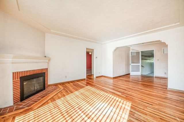 unfurnished living room with a brick fireplace and wood-type flooring