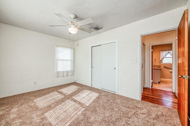 unfurnished bedroom with multiple windows, carpet floors, a closet, and ceiling fan