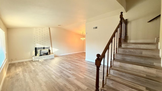 1859 S Karen Ave, Fresno, CA 93727 - unfurnished living room with wood finished floors, stairs, a brick fireplace, lofted ceiling, and baseboards