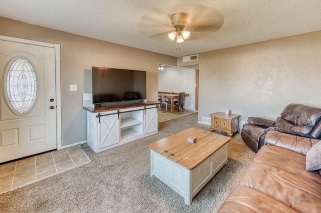 living room featuring ceiling fan, light colored carpet, and a textured ceiling