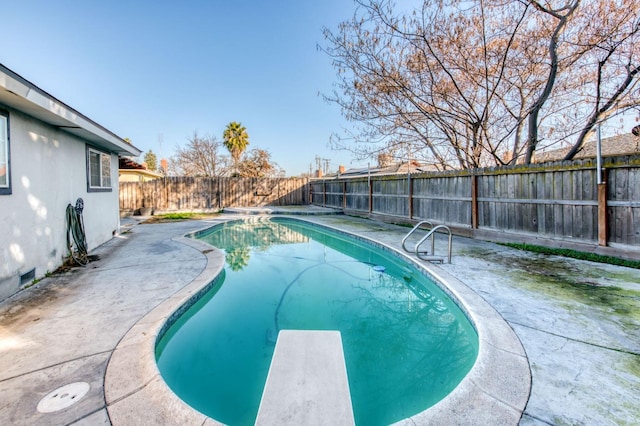 view of swimming pool featuring a diving board and a patio