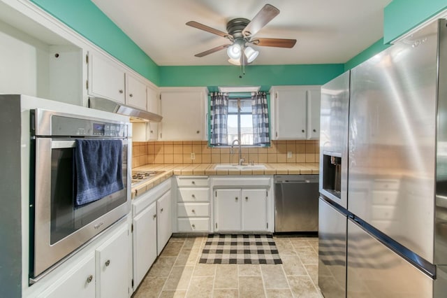 kitchen featuring white cabinetry, sink, decorative backsplash, tile counters, and stainless steel appliances