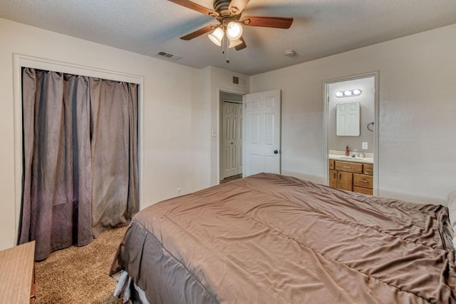 bedroom featuring ensuite bathroom, a textured ceiling, carpet flooring, a closet, and ceiling fan