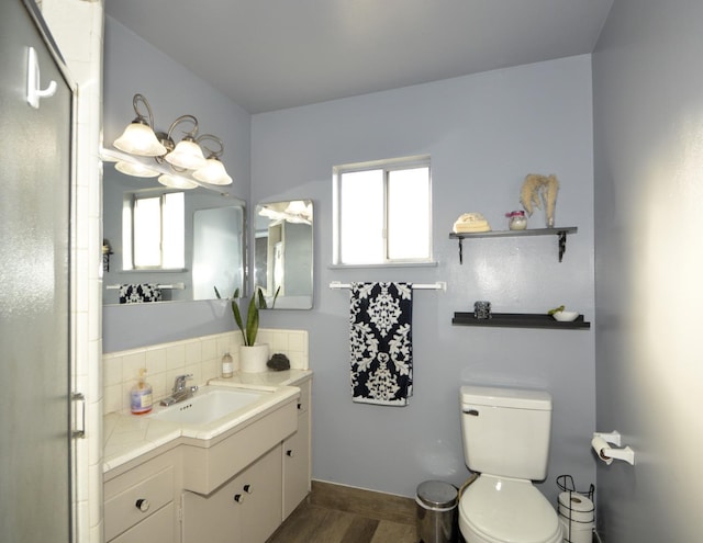 bathroom featuring tasteful backsplash, a shower stall, toilet, and vanity