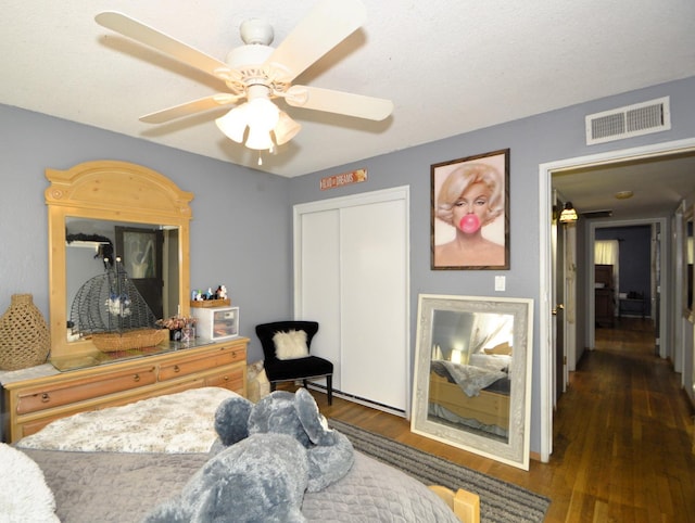 bedroom with a closet, visible vents, a ceiling fan, and wood finished floors