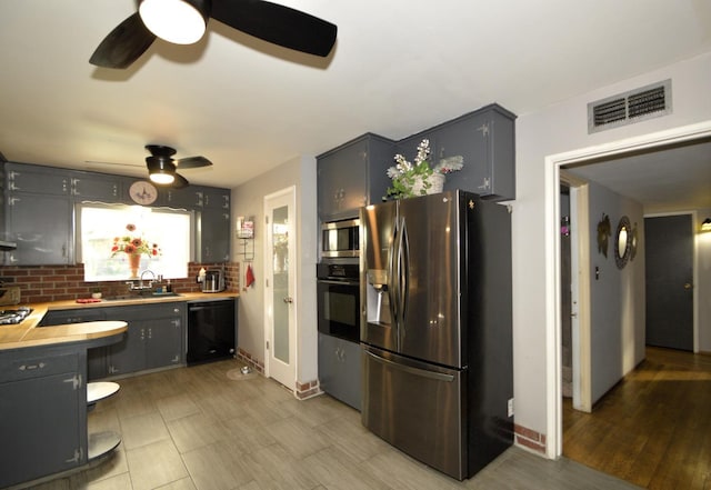 kitchen with visible vents, light countertops, decorative backsplash, black appliances, and a sink