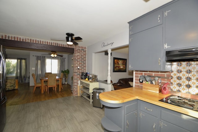 kitchen with light wood finished floors, gas stovetop, gray cabinets, light countertops, and under cabinet range hood