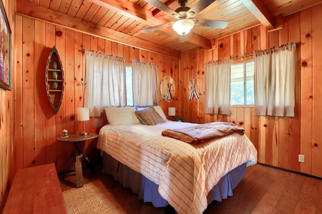 bedroom featuring beamed ceiling, ceiling fan, wooden walls, and multiple windows