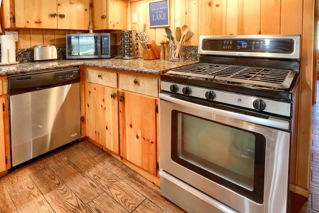 kitchen with light wood-type flooring, light stone countertops, wooden walls, and appliances with stainless steel finishes