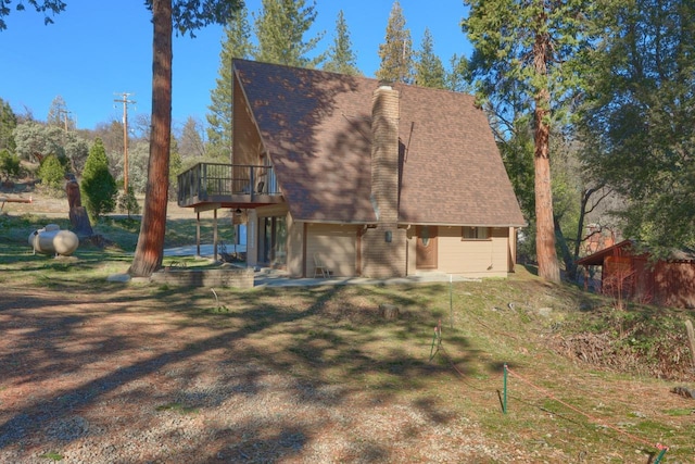 back of property featuring a garage, a deck, and a lawn