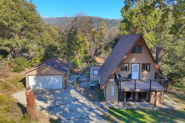 view of front of house with an outbuilding, a garage, a deck with mountain view, and a patio