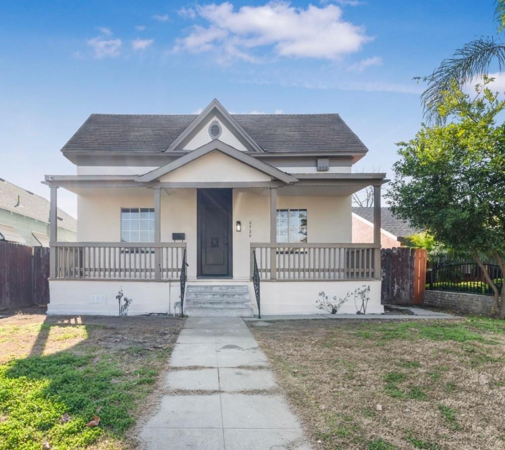 bungalow-style home featuring covered porch and a front lawn