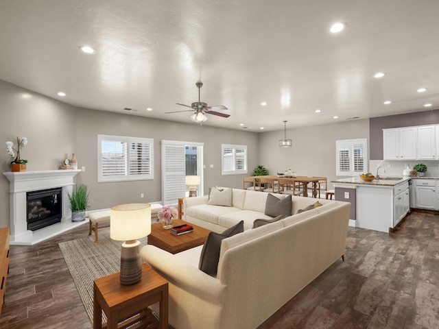 living room featuring dark wood-type flooring, ceiling fan, plenty of natural light, and sink