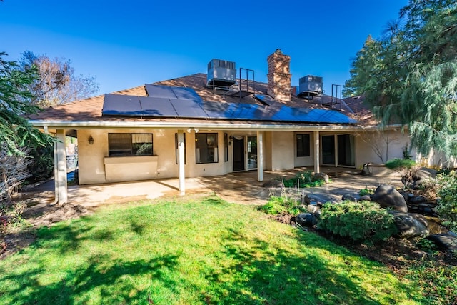 rear view of house with central AC unit, a patio area, solar panels, and a lawn