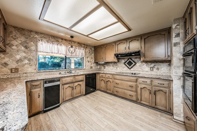 kitchen featuring sink, light hardwood / wood-style flooring, hanging light fixtures, black appliances, and light stone countertops