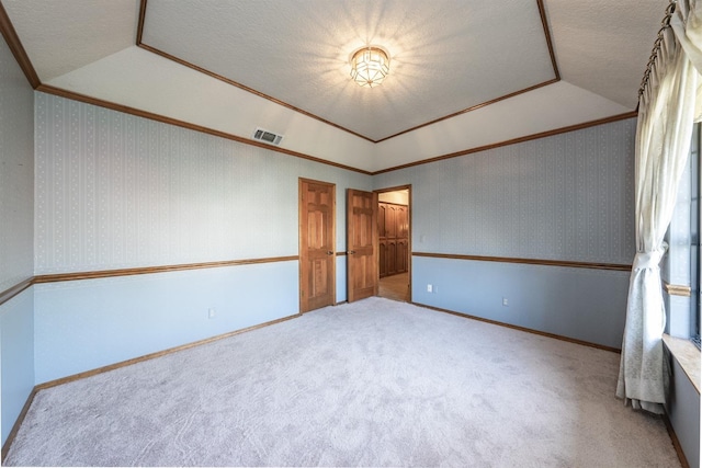 unfurnished room featuring vaulted ceiling, carpet floors, and crown molding