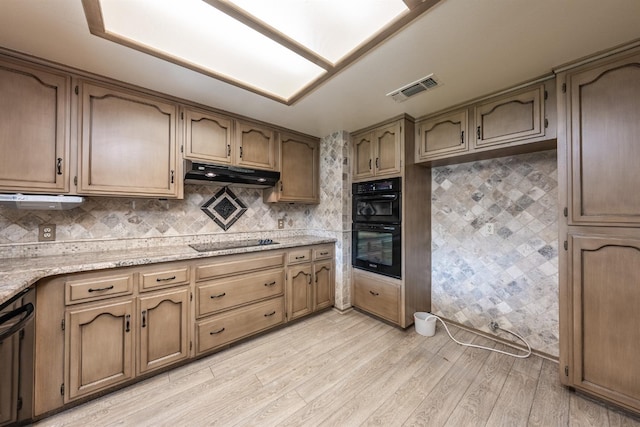 kitchen featuring light stone counters, decorative backsplash, light hardwood / wood-style flooring, and black appliances