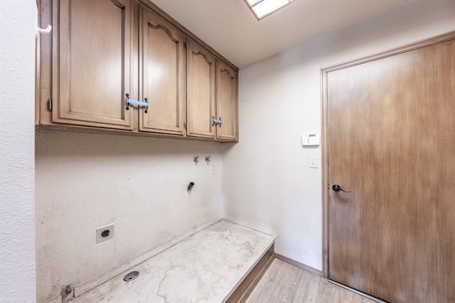 laundry room featuring electric dryer hookup, hookup for a gas dryer, light hardwood / wood-style flooring, and cabinets