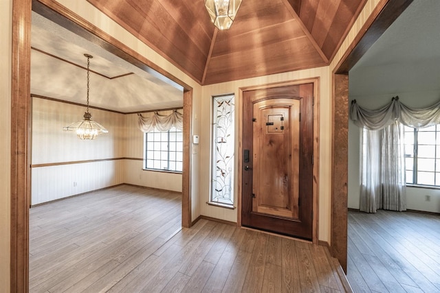 foyer with vaulted ceiling, plenty of natural light, wood-type flooring, and a chandelier