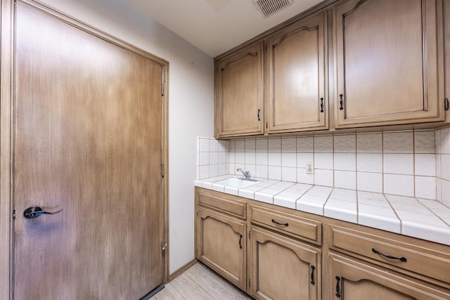 kitchen featuring tasteful backsplash, sink, and tile countertops