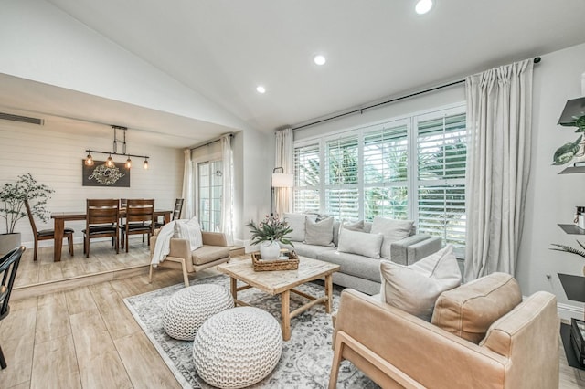 living room with lofted ceiling, an inviting chandelier, and light wood-type flooring