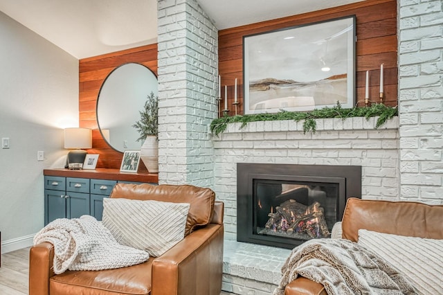 sitting room with lofted ceiling, a fireplace, and light wood-type flooring