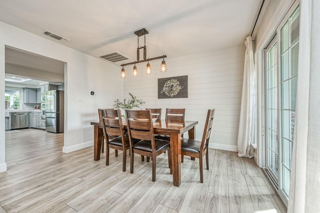 dining area featuring wooden walls and light hardwood / wood-style flooring