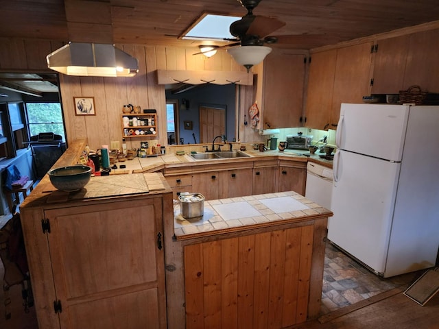 kitchen featuring sink, wood walls, tile counters, kitchen peninsula, and white appliances