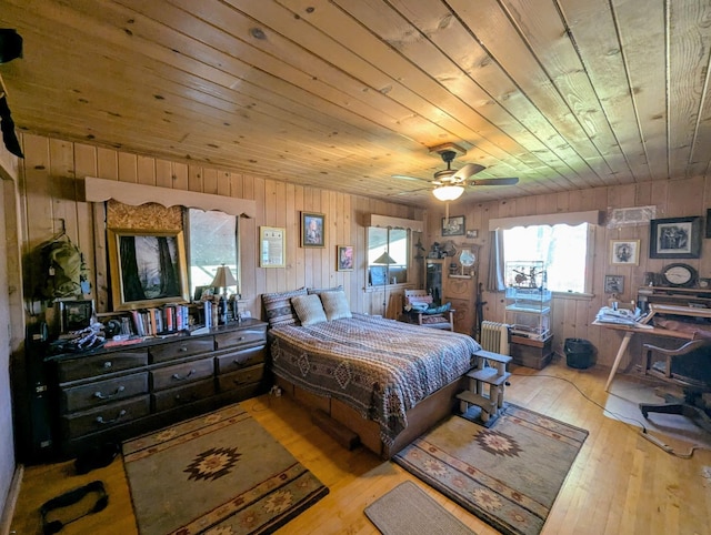 bedroom featuring radiator, wood walls, ceiling fan, wood ceiling, and light hardwood / wood-style floors