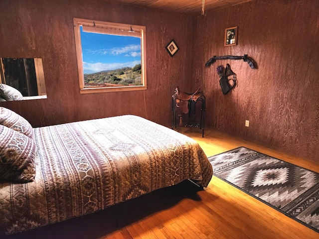 bedroom with hardwood / wood-style floors, wood ceiling, and wooden walls